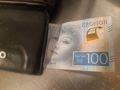 En 100-kronorssedel som sticker ut ur en plånbok